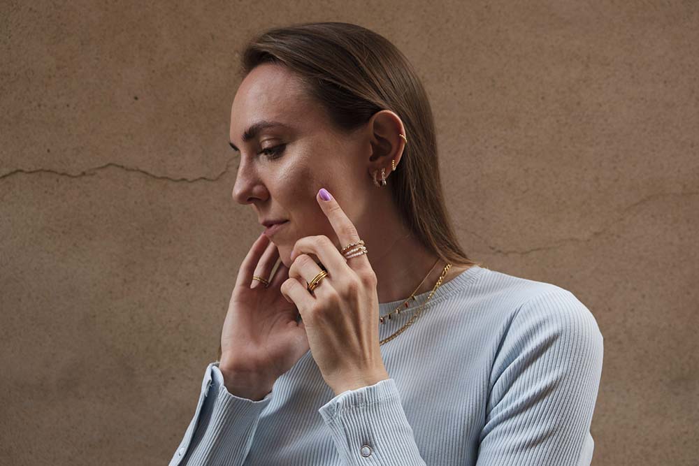Mujer joven. Lleva varios pendientes y piercings en la oreja izquierda.